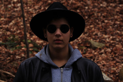 Young woman wearing hat and sunglasses standing at forest