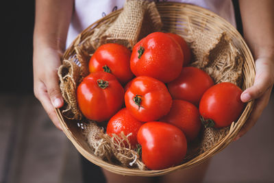 Low section of woman holding strawberries in basket
