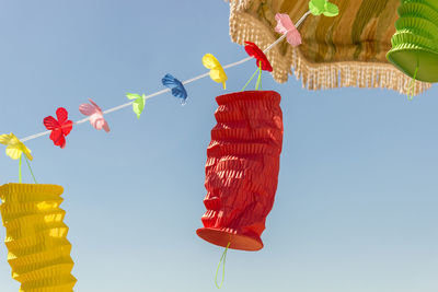 Low angle view of multi colored umbrellas hanging against clear sky