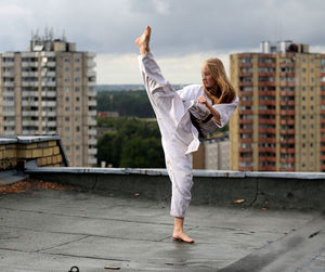 Full length of young woman standing against building