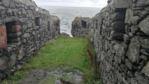 Stone wall by sea against sky