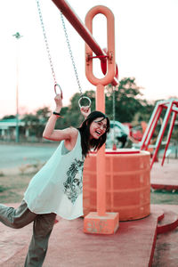 Cheerful woman holding rings while standing at park