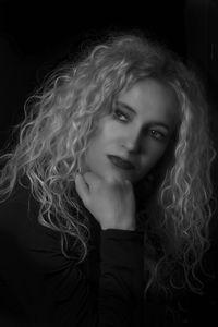 Close-up of beautiful mature woman looking away against black background