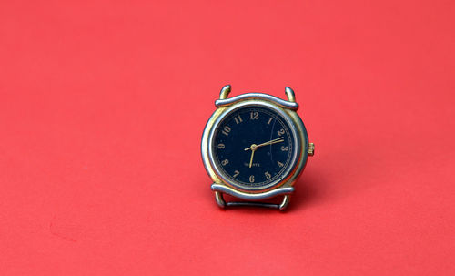 Close-up of antique clock against red background