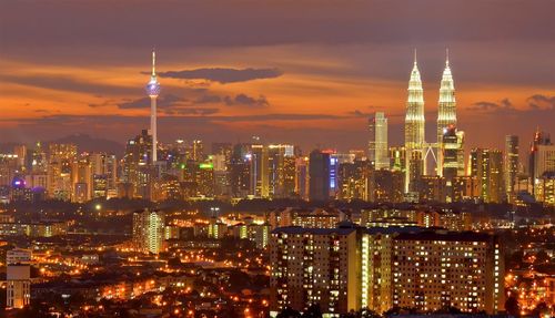 Illuminated buildings in city against sky at night