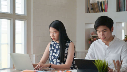 Young woman using phone while sitting in office