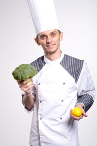 Portrait of smiling man holding apple against white background