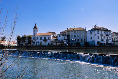 Buildings in city against clear blue sky