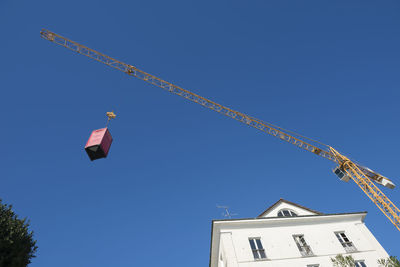 Low angle view of container on crane against clear blue sky