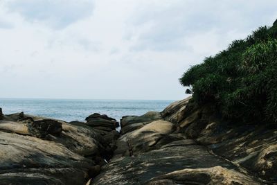 Rocks by sea against sky