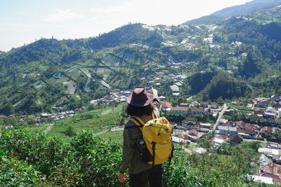 Man with yellow backpack in the highland area of the slopes of mount lawu, indonesia