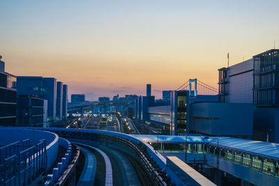 High angle view of railroad tracks by buildings against sky during sunset