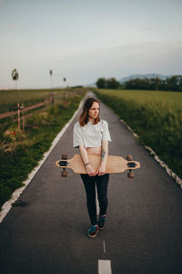 Portrait of young woman using mobile phone while standing on road