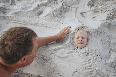 High angle view of father and son on sand at beach