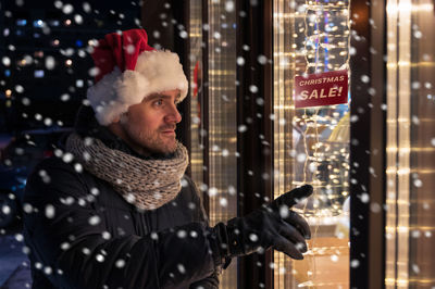 Smiling man touching window glass during winter