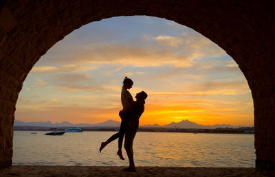 Silhouette woman standing at beach during sunset