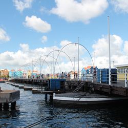 Sailboats moored at harbor against sky in city