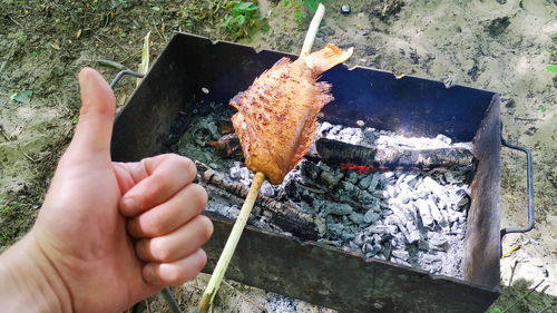 High angle view of person hand on barbecue grill