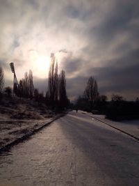 Road passing through landscape against cloudy sky