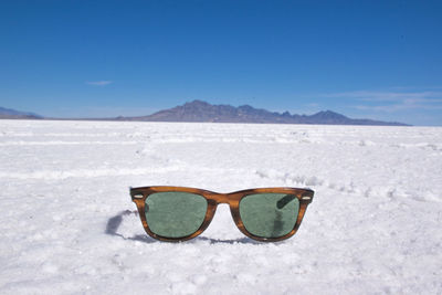 Sunglasses on beach against sky