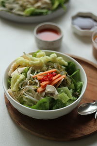 High  angle view of indonesian spicy salad, topped with peanut sauce on the table.