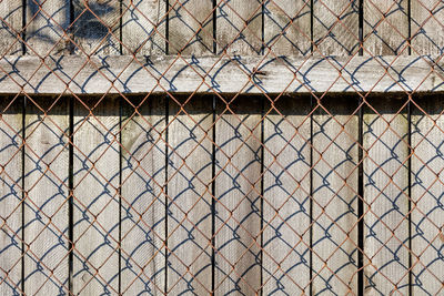 The weathered old gray wooden fence is closed by a rusted netting netting.