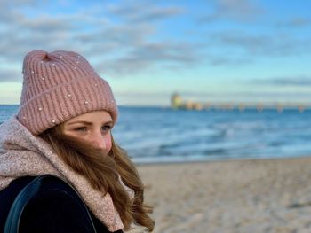 Portrait of woman wearing hat against sea during winter