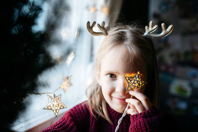 Portrait of little smiling girl playing with christmas lights 