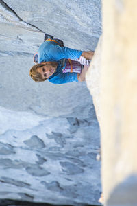 Rock climber looking up while climbing in yosemite, el capitan