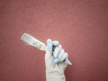 Cropped hand of woman holding bottle against yellow background