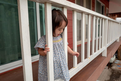 Cute baby girl standing by railing in balcony