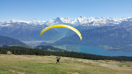 Man paragliding over mountain against sky