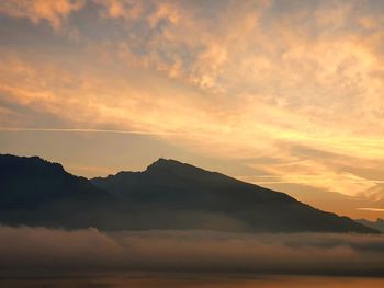 Scenic view of dramatic sky over silhouette mountains during sunset