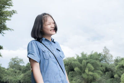 Beautiful young woman looking at camera against sky