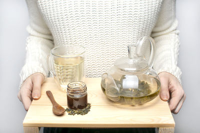 Midsection of woman holding coffee cup and jar on table
