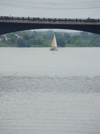 Sailboat sailing on river against sky