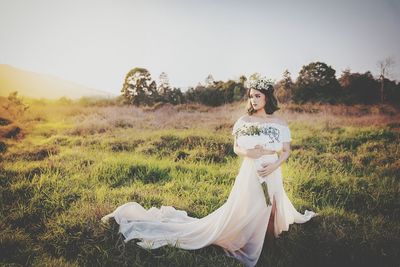 Portrait of happy woman standing on field against clear sky