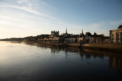 View of river by buildings against sky in city