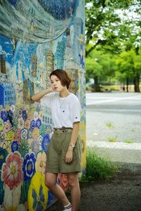 Full length of a young woman standing against plants