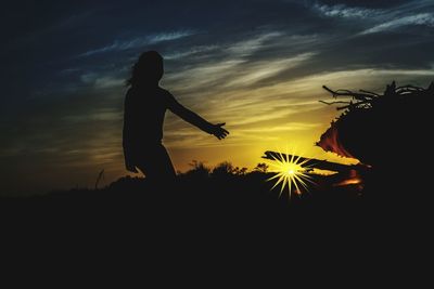 Silhouette woman standing by tree against sky during sunset