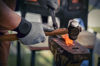 Cropped image of manual worker hitting molten metal