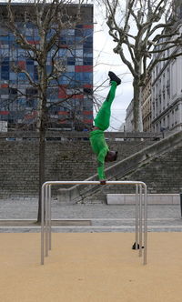 Side view of man doing handstand on railing at playground