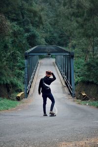 Full length of man standing on road against trees