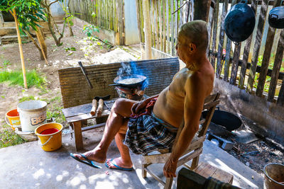 Full length of senior man cooking while sitting on chair