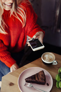 Women taking food photo on smart phone. cake mobile photography in cafe