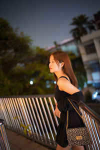 Portrait of young woman sitting on railing