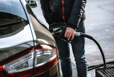 Midsection of man holding camera while standing by car