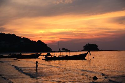 Silhouette people on sea against sky during sunset