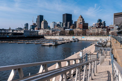 Bridge over river by buildings in city against sky