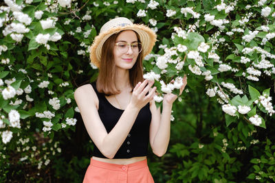 Beautiful young woman standing by flowering plants